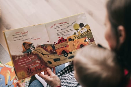 woman reading book to toddler