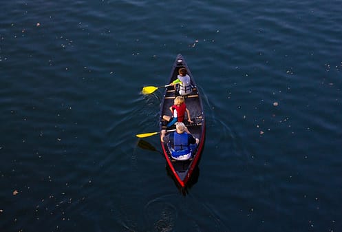 people riding red canoe boat