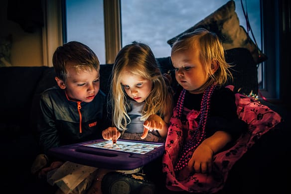 three children looking at a tablet computer